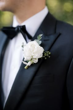 a man in a tuxedo with a white flower on his lapel coat