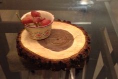 a bowl of fruit sitting on top of a wooden slice