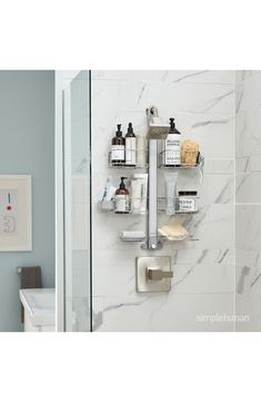 a bathroom with white marble walls and shelves holding personal care items, such as toiletries and soaps