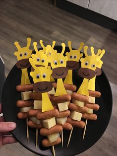 a black plate topped with lots of hot dogs covered in cheese and giraffe faces