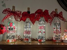 three empty bottles with red bows and lights in them sitting on a table next to flowers