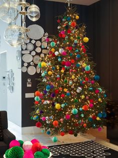 a living room with a christmas tree in the corner and decorations on the wall behind it