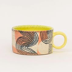 a yellow and black coffee cup sitting on top of a white table