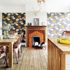 a dining room table with chairs and a fire place in front of a wallpapered fireplace