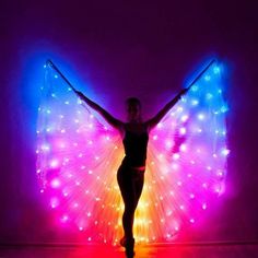 a woman is standing in front of a colorful light up butterfly wings wall hanging from the ceiling