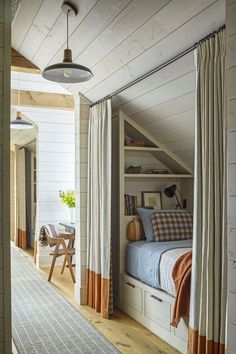 an attic bedroom with white walls and wood flooring, built into the side of a house