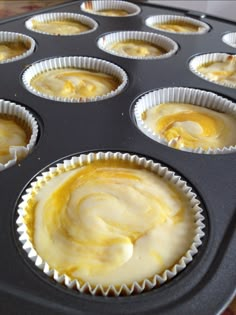 cupcakes with yellow icing sitting in a muffin tin