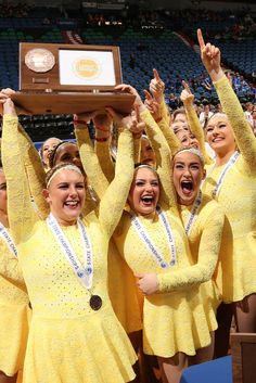 the cheerleaders are holding up their trophy and posing in front of an audience