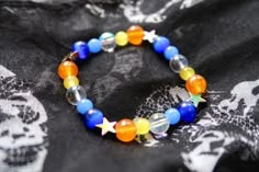 Aroace pride flag star beaded gemstone bracelet. The beads are the aroace flag colors (orange, yellow, white, blues) and holographic stars. ♥ Bracelet Size: - To find the size that fits you best, you can measure the circumference around your wrist; for a comfort/loose fit, add 2cm to that measurement ♥ Handcrafted With: ✔ High-quality gemstone beads ✔ Durable stretchy cord Thank you for visiting! If you have any questions, feel free to contact me!  Instagram: @FrogsMakingToast Pride Beaded Necklace, Handmade Multicolor Star Bracelets, Multicolor Star-shaped Bracelet With Colorful Beads, Rainbow Star-shaped Bracelet For Gift, Colorful Star-shaped Jewelry For Gifts, Aroace Kandi, Handmade Star-shaped Multicolor Jewelry, Handmade Multicolor Star-shaped Jewelry, Handmade Rainbow Star Jewelry