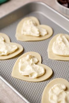 heart shaped cookies with cream frosting on a cookie sheet