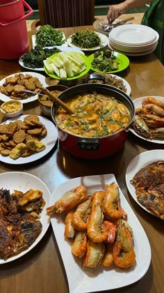 a table filled with plates and bowls full of different types of food, including shrimp