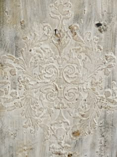 an old wall with peeling paint and designs on the side, in white or grey colors