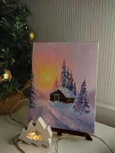 a painting on a table next to a christmas tree and a small light bulb holder