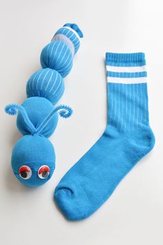 a blue sock with two balls attached to it next to a stuffed toy bug on a white surface