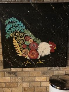 a rooster painted on the side of a brick wall next to a trash can