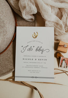 the wedding stationery is laid out on top of an old hat and other items