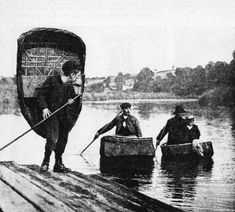 an old photo of three men in the water with luggage on their backs and one holding a fishing rod