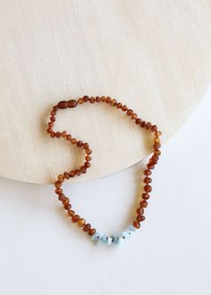 a beaded necklace on a white surface with a wooden disc in the back ground