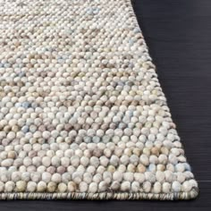 an area rug with many balls on the floor and black wood floors in front of it