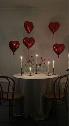 the table is set with candles and heart shaped balloons