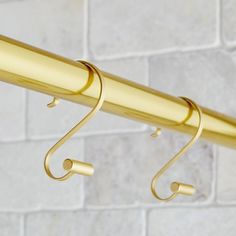 a close up of a gold curtain rod on a white brick wall in the background