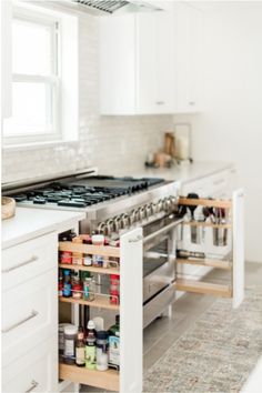 an open drawer in the middle of a kitchen with white cabinets and counter top space