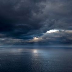 the sky is filled with dark clouds over the ocean