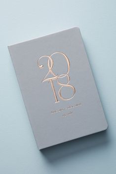 a silver and gold wedding guest book on a light blue background with the letter g