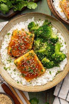 two plates filled with rice, broccoli and tofu on top of each other