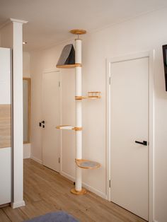 a cat tree in the corner of a room next to a door and television set