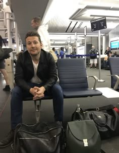 a man sitting in an airport waiting for his luggage