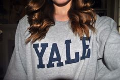 a woman with long brown hair wearing a gray sweatshirt