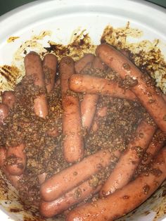 a bunch of hot dogs in a white bowl with brown stuff on top and sprinkles all over them