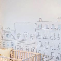 a baby's crib in front of a wall with buildings drawn on it