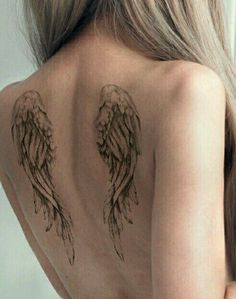 an angel wing tattoo on the back of a woman's shoulder