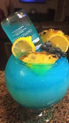 a blue drink in a glass with lemon wedges