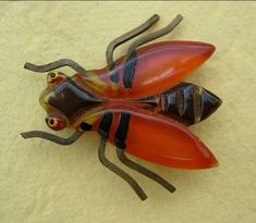 two glass bugs sitting next to each other on top of a white surface with yellow and red colors