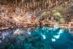 the inside of a cave with blue water