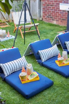 two blue lounge chairs sitting on top of a lush green field