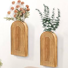 two wooden vases with flowers in them on the wall