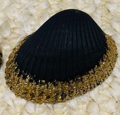 a black and gold hat sitting on top of a pile of white fur covered ground