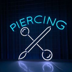 a neon sign that says piercing with a pair of scissors in front of the word