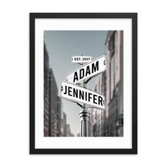 a black and white photo of two street signs in front of tall buildings with the words adam and jennifer on them