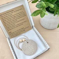 an open box with a keychain and some beads in it sitting on a table next to a potted plant