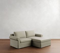 a white couch sitting on top of a wooden floor next to a chair and ottoman