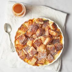 a dessert with powdered sugar sits on a napkin next to a cup of tea