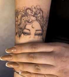 a woman's arm with a tattoo on it and flowers in her hair,