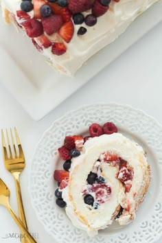 a piece of cake on a plate with berries and whipped cream in the middle next to a fork