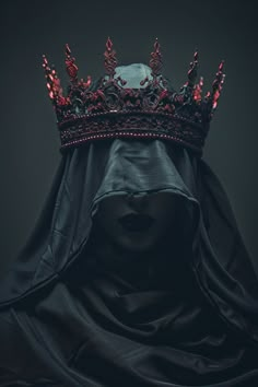 a woman wearing a black veil with a crown on her head and red lights in the middle