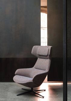 a chair sitting on top of a metal base in front of a wall with a window